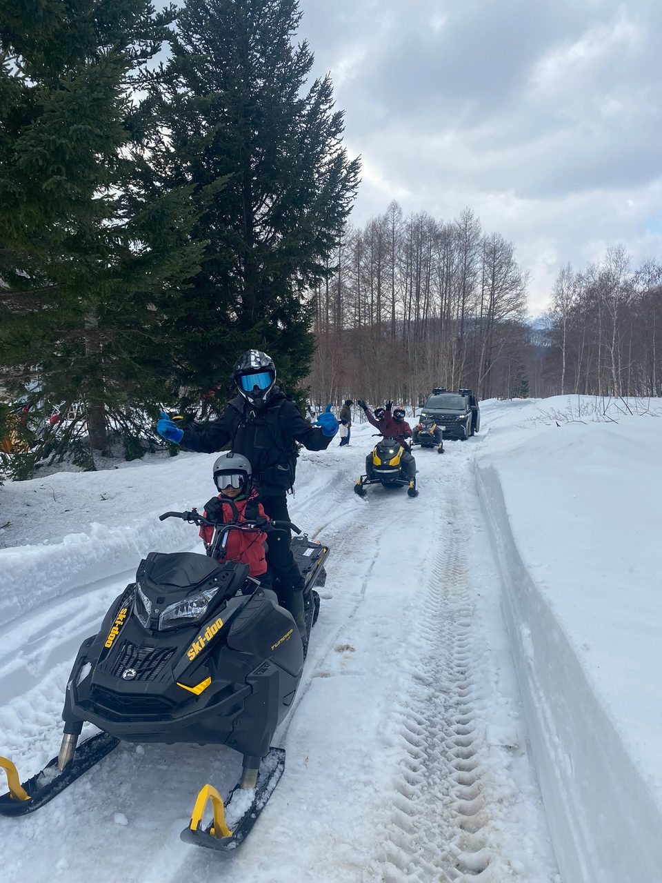 Guide and a young passenger on a snowmobile during a family-friendly Niseko tour
