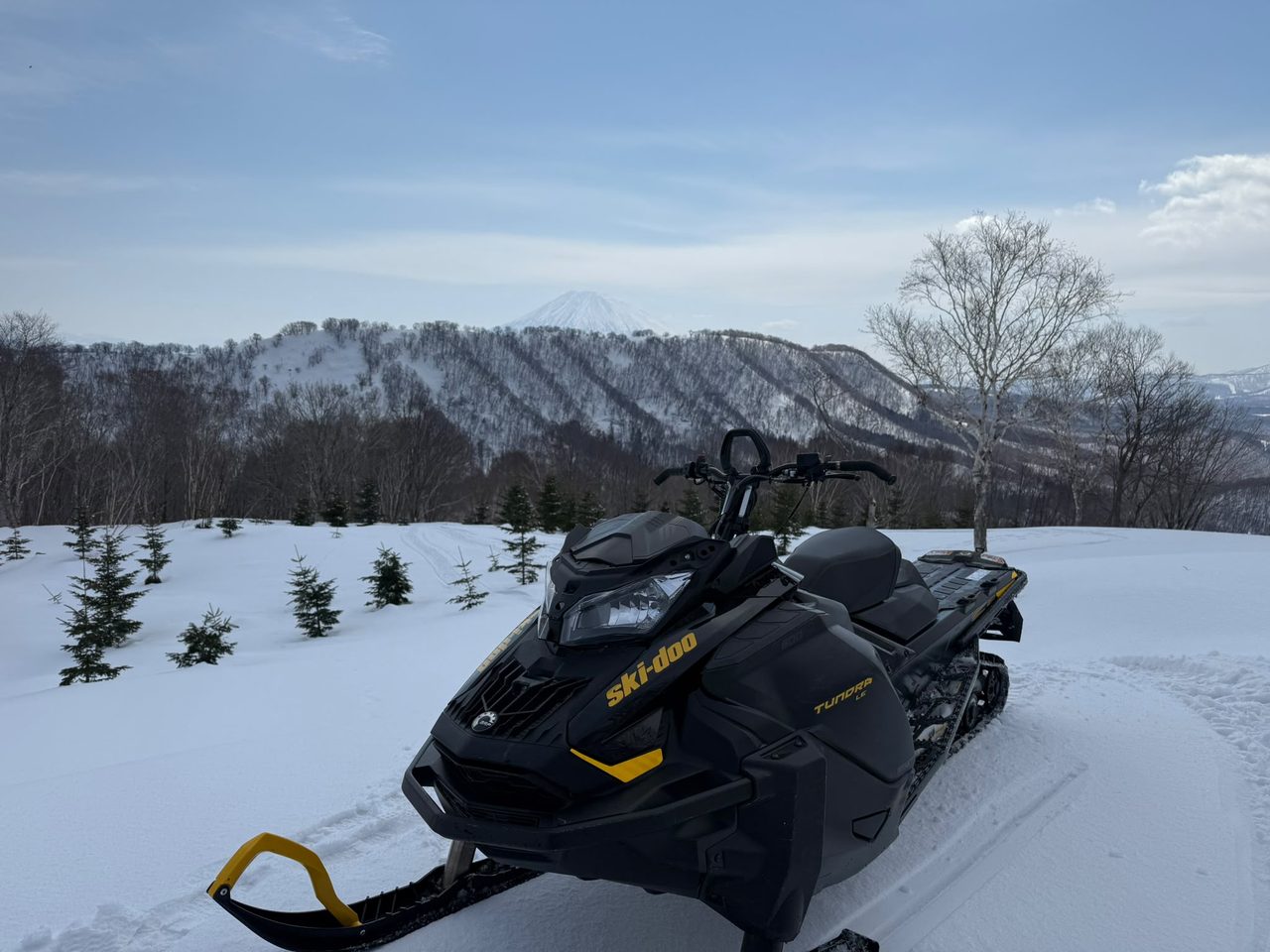 Ski-Doo snowmobile parked on a backcountry ridge in Niseko with Mt Yotei in the distance