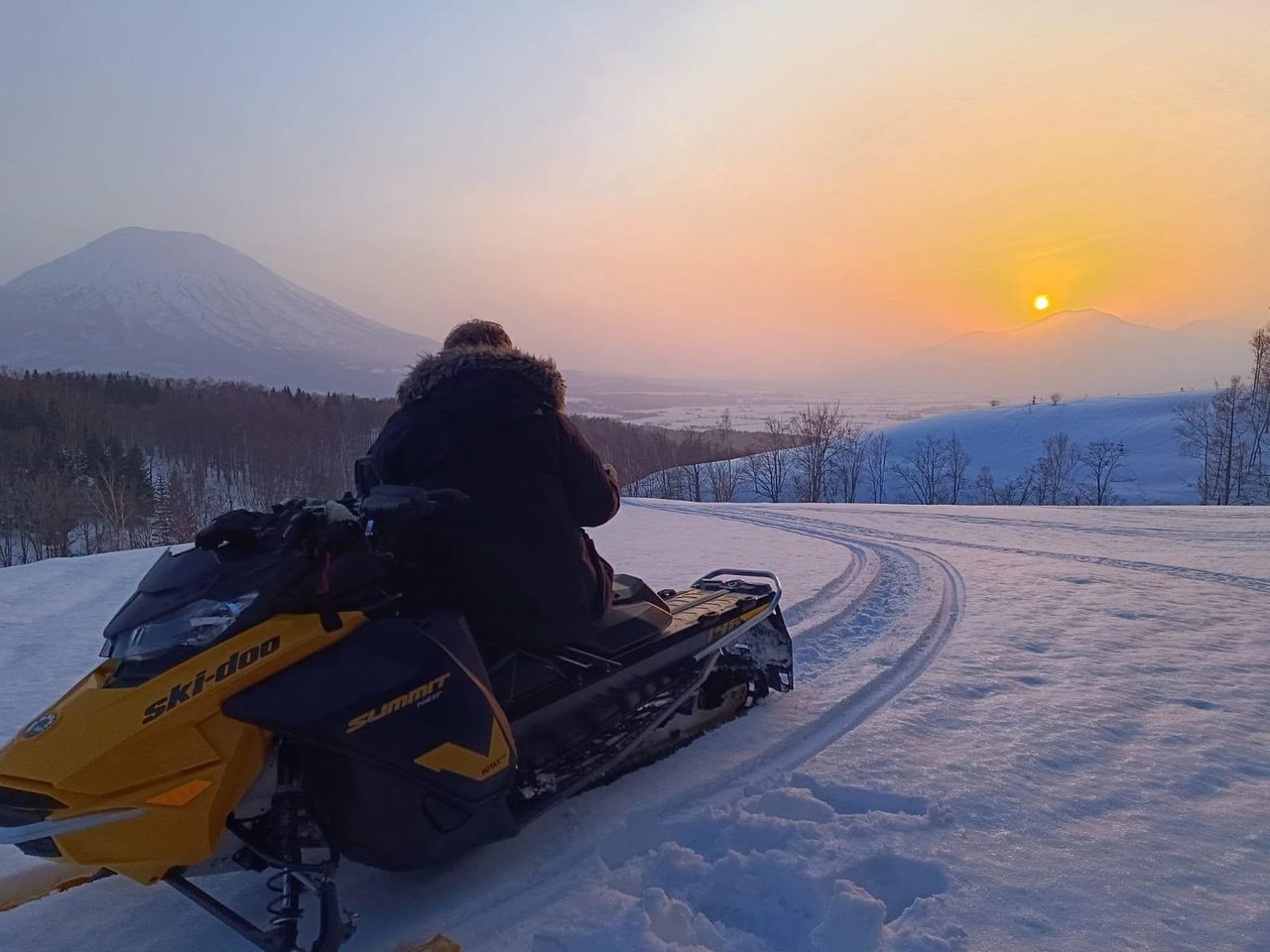 Snowmobile rider watching the sunset over Mt Yotei on a Niseko backcountry tour