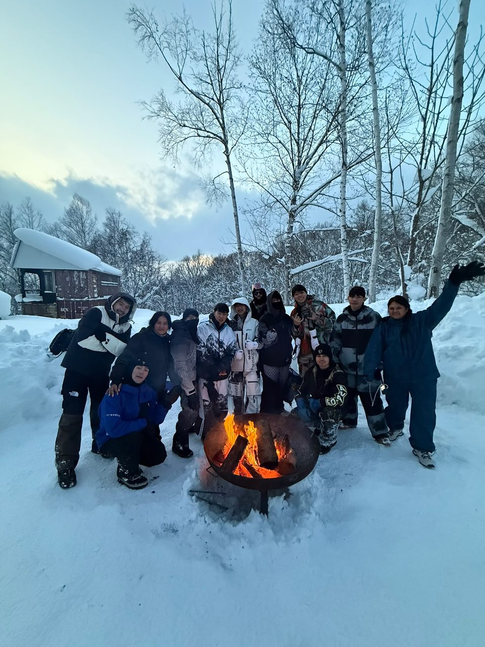 Tour group gathered around a fire pit in the snow after a Niseko snowmobile tour